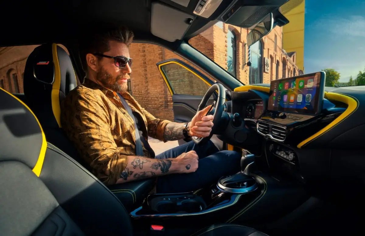 Mann sitzt im stylischen Innenraum eines Nissan JUKE und nutzt das Multimediasystem.