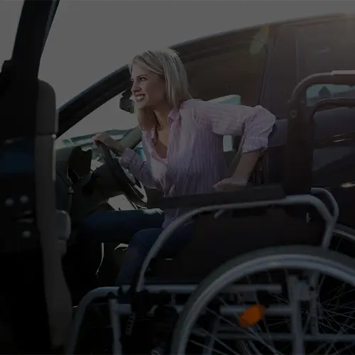 Frau im Rollstuhl steigt eigenständig aus einem barrierefreien Fahrzeug aus.