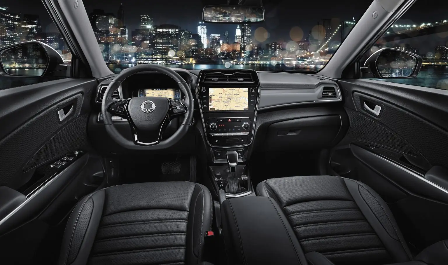 Fahrerorientierter Innenraum des KGM Tivoli mit schwarzem Lederinterieur und Touchscreen-Navigation bei Nacht.