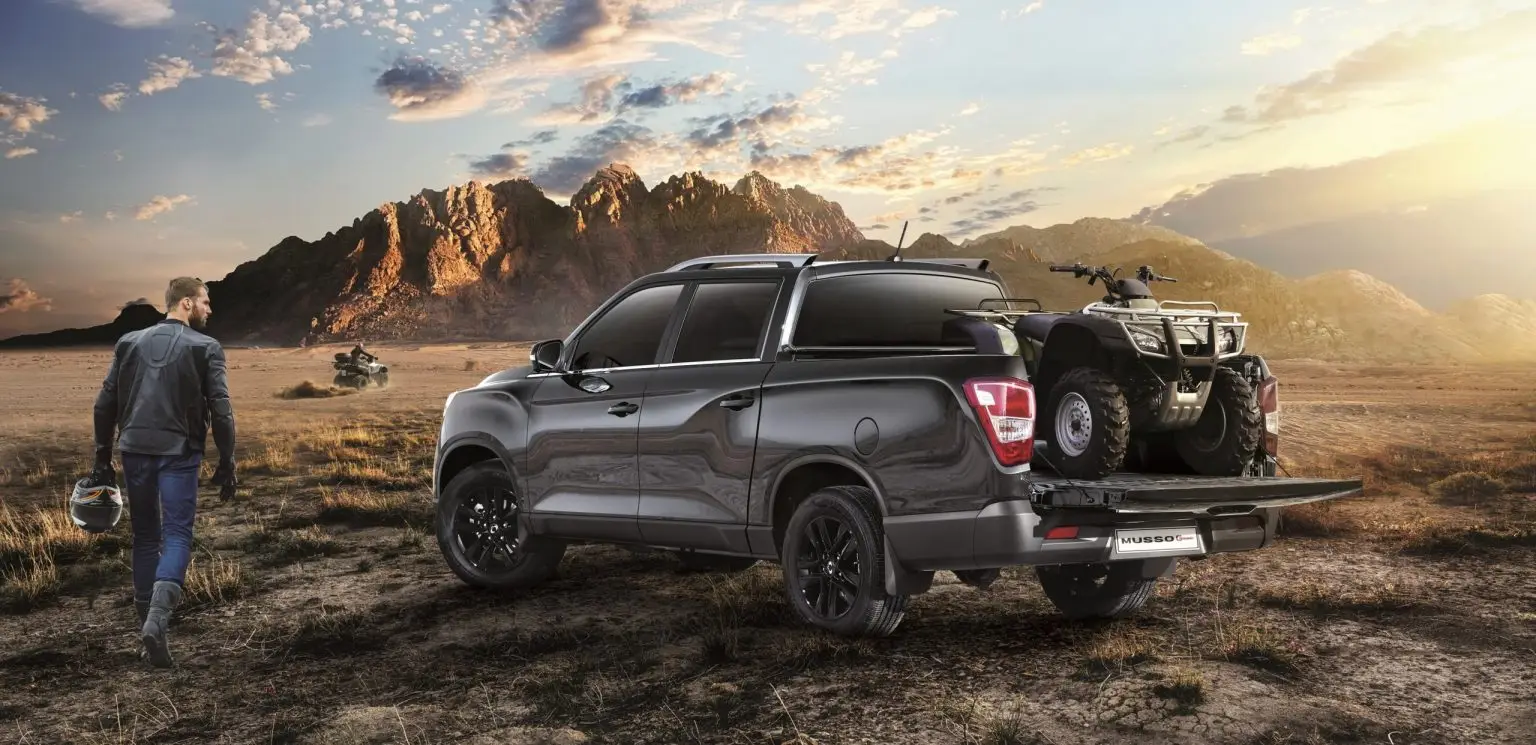 KGM Musso Grand mit Quad auf Ladefläche in der Wüste bei Sonnenuntergang