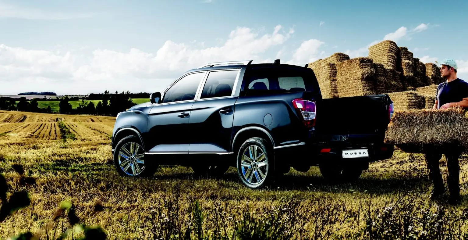 KGM Musso Pick-up auf Feld mit Landwirt und Heuballen.