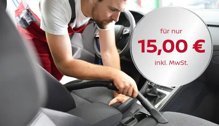 Ein Staubsaugerrohr wird zur Reinigung in den Fahrzeuginnenraum gehalten.