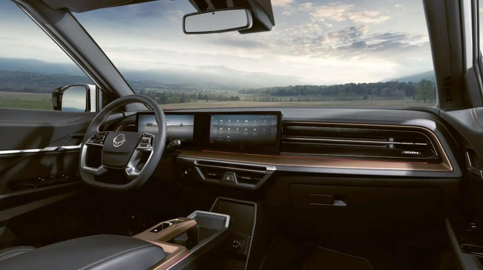 Modernes Cockpit des vollelektrischen KGM Torres EVX mit digitalem Display und Blick auf die Natur durch die Frontscheibe.