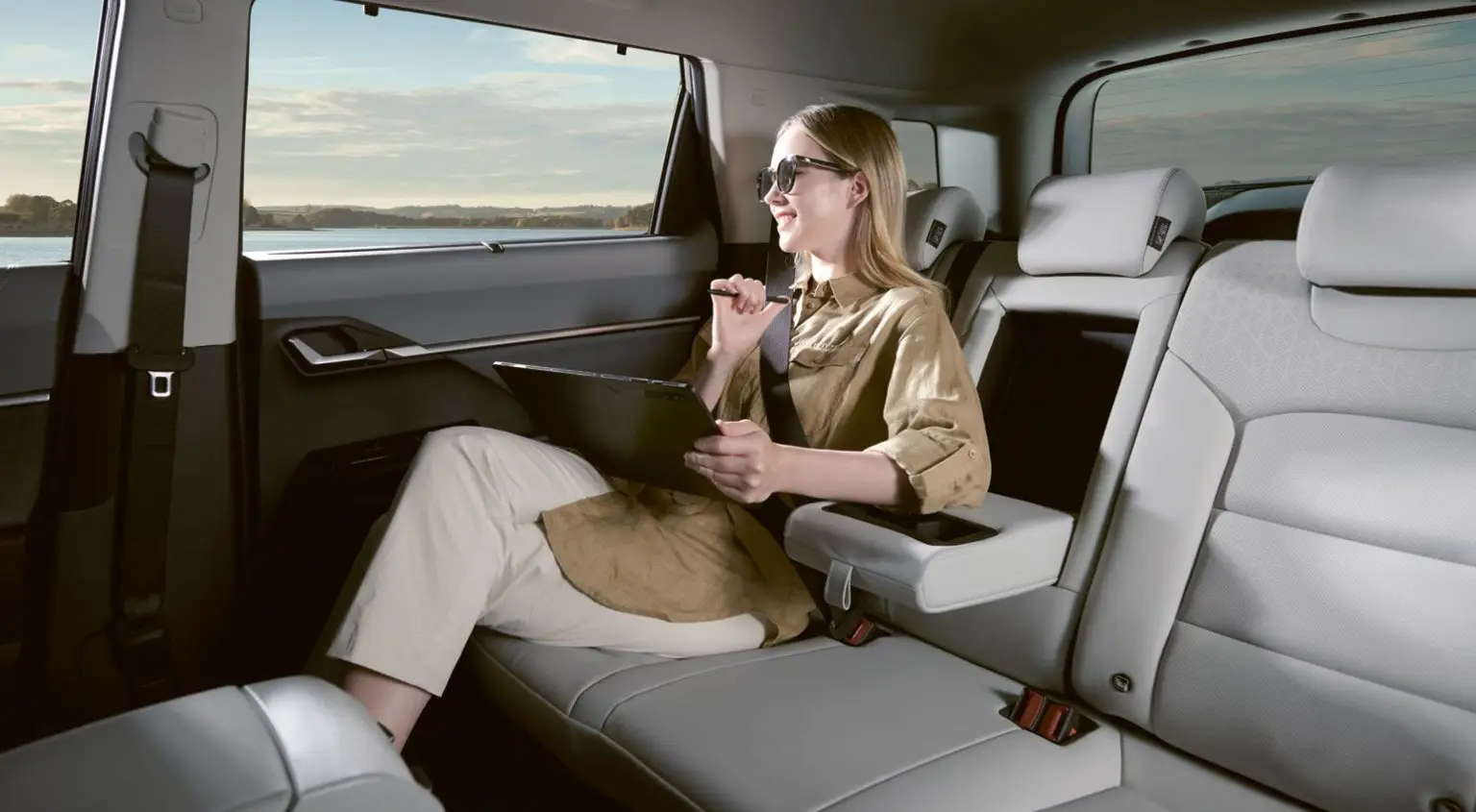 Komfortabler Rücksitzbereich im KGM Torres EVX mit großzügigem Platzangebot und eleganter Ausstattung – eine Frau arbeitet entspannt mit einem Tablet.